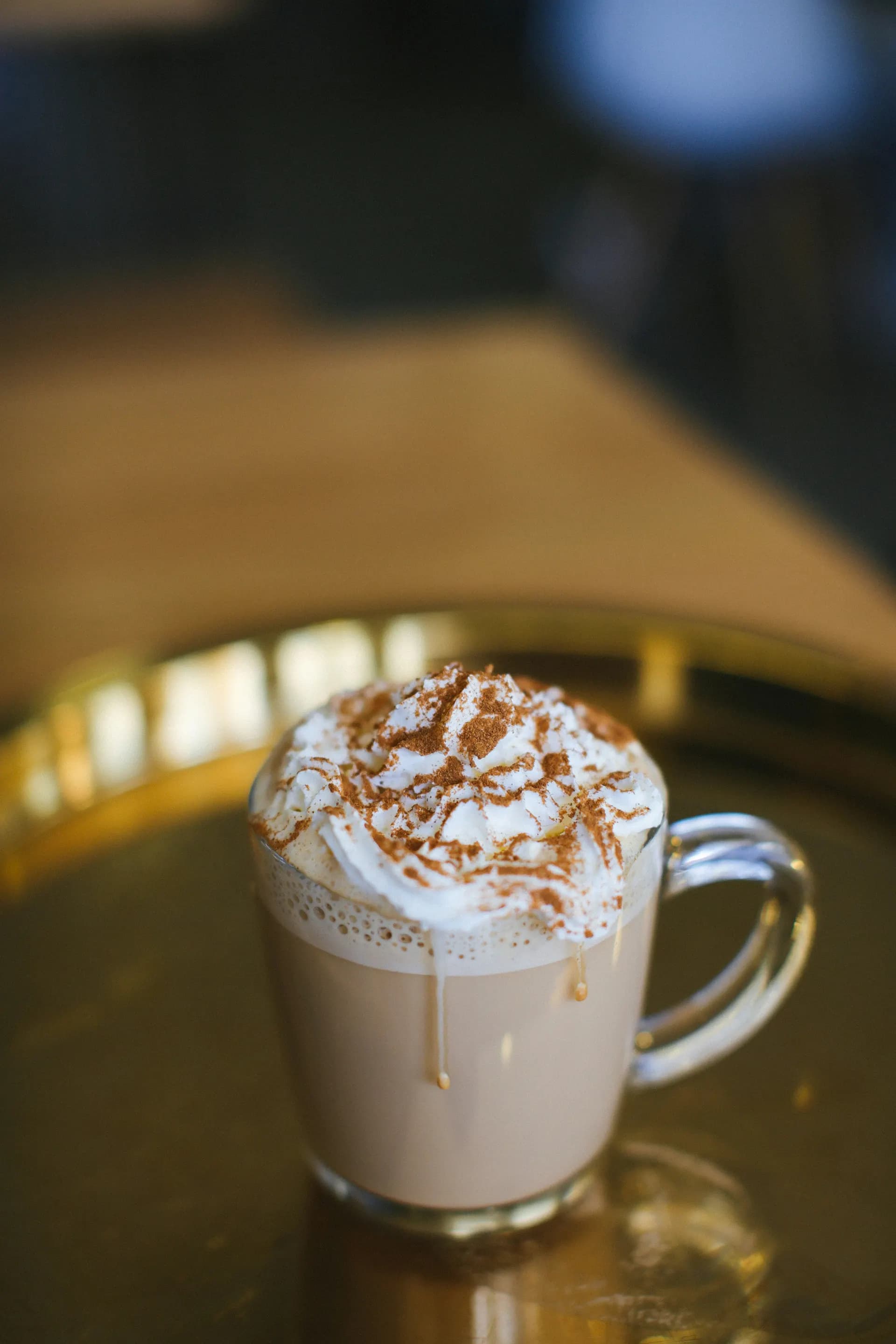 Cappuccino con canela y crema en bandeja dorada