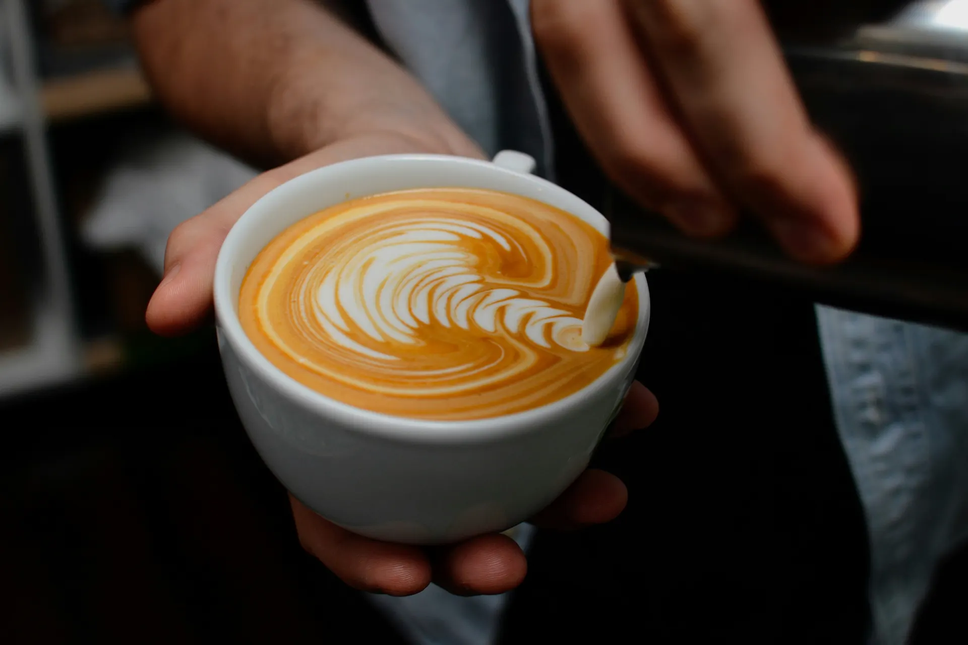 Barista preparando latte art en taza blanca