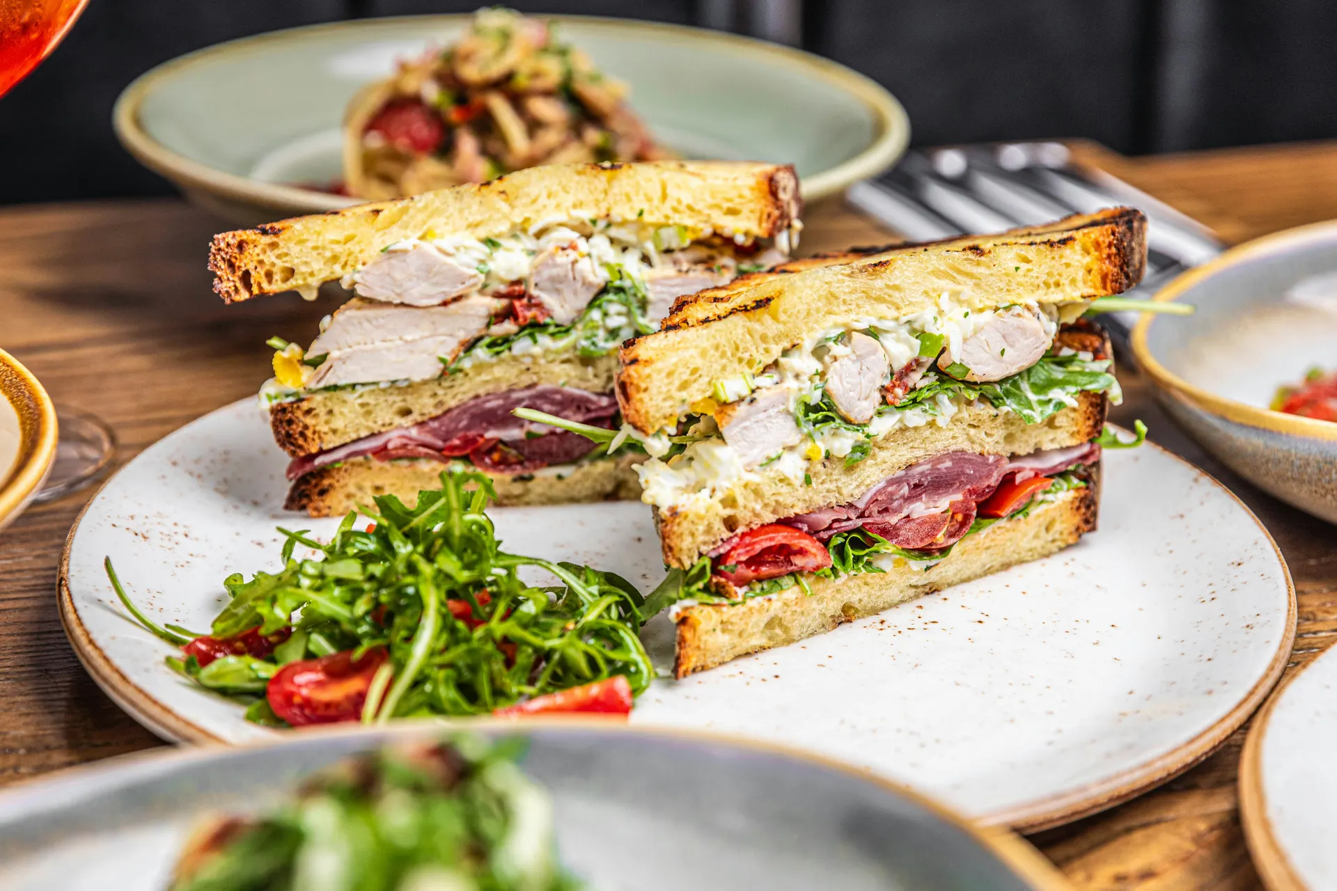 Sandwich gourmet con rúcula en plato cerámico